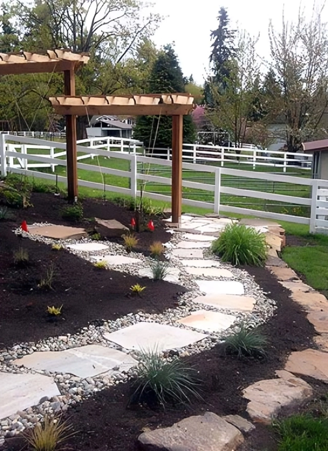 Garden path with pergola and white fence.